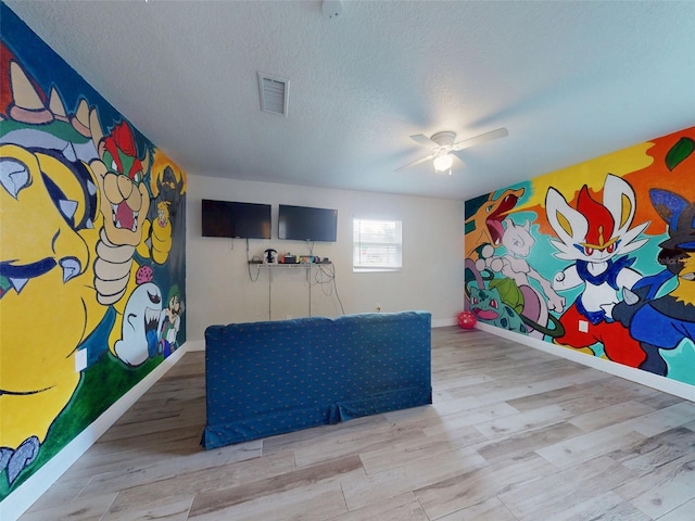 recreation room with a textured ceiling, wood finished floors, visible vents, and a ceiling fan