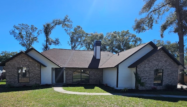 view of front of home featuring brick siding, roof with shingles, a chimney, and a front yard