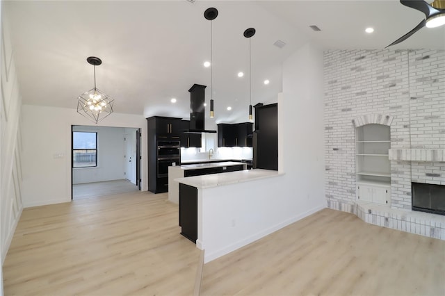 kitchen with open floor plan, a peninsula, light countertops, dark cabinetry, and black appliances