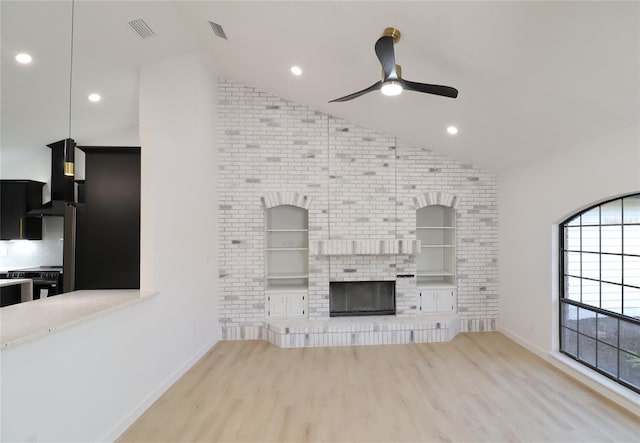 unfurnished living room with lofted ceiling, ceiling fan, a fireplace, wood finished floors, and visible vents