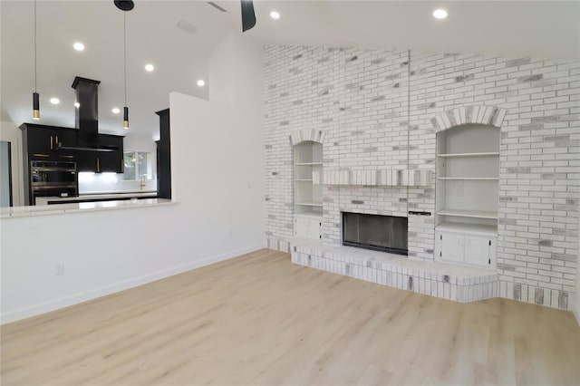 unfurnished living room featuring a brick fireplace, baseboards, wood finished floors, and recessed lighting