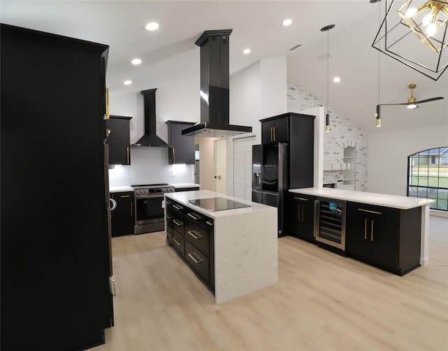 kitchen featuring stainless steel electric stove, hanging light fixtures, a kitchen island, wall chimney range hood, and dark cabinetry