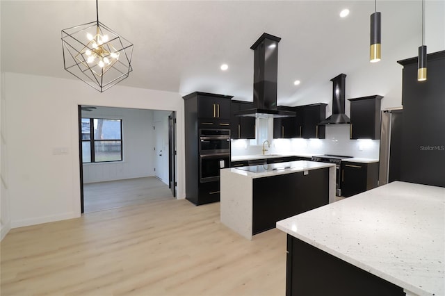 kitchen featuring pendant lighting, a kitchen island, island range hood, dark cabinetry, and wall chimney exhaust hood