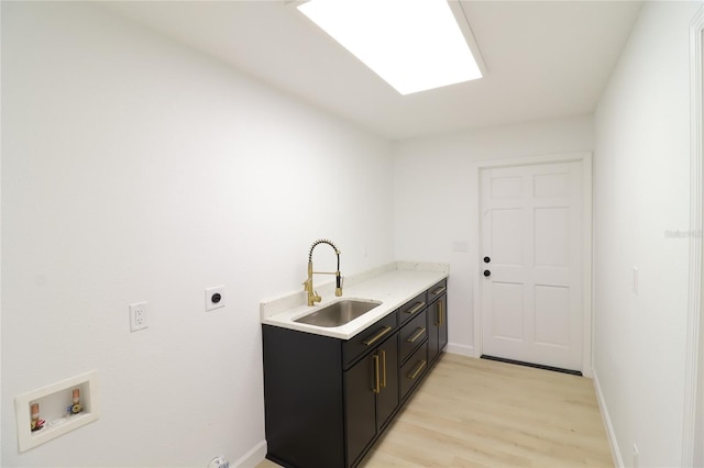 laundry room featuring cabinet space, hookup for an electric dryer, light wood-type flooring, washer hookup, and a sink