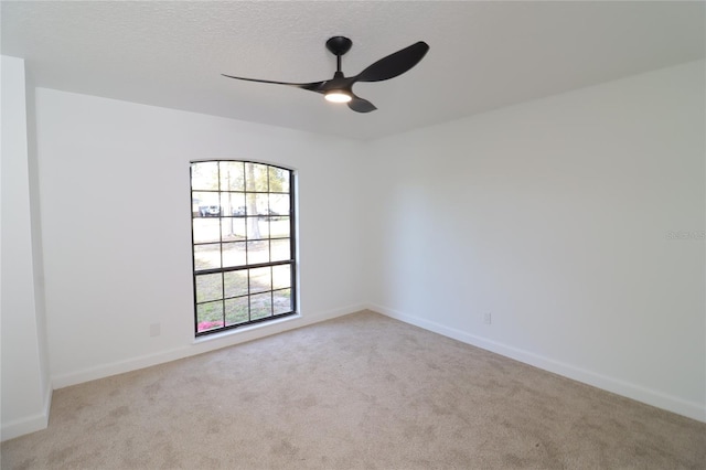 spare room with baseboards, ceiling fan, a textured ceiling, and light colored carpet