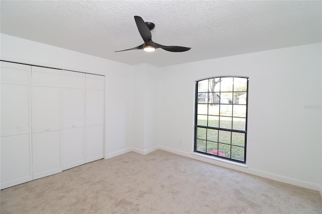 unfurnished bedroom with a closet, light colored carpet, and a textured ceiling