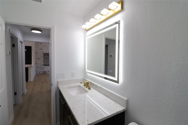 bathroom with a textured wall, wood finished floors, and vanity