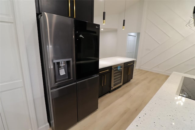 kitchen featuring stainless steel fridge with ice dispenser, light wood-style flooring, wine cooler, decorative light fixtures, and light stone countertops