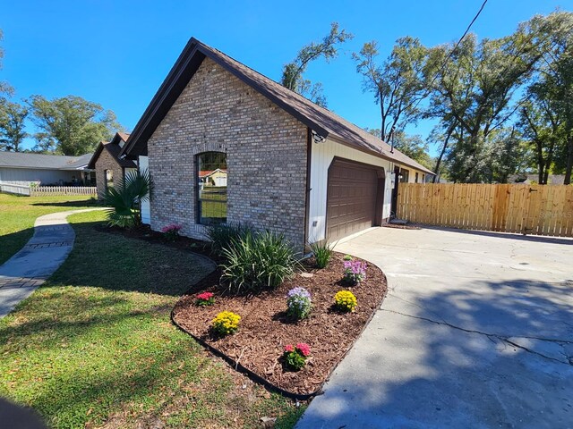 view of home's exterior featuring brick siding, a yard, fence, a garage, and driveway