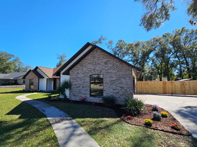 view of front of house with brick siding, a front yard, and fence