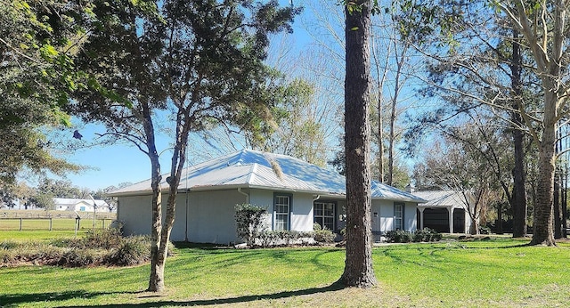 view of side of home featuring a lawn, fence, and stucco siding