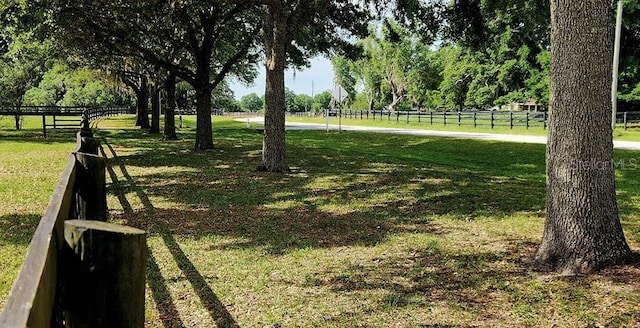 view of property's community featuring a rural view, fence, and a yard