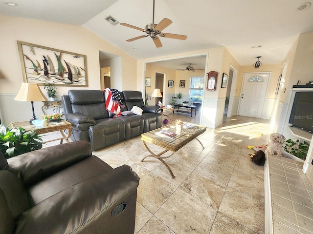 living area featuring vaulted ceiling, wainscoting, and visible vents