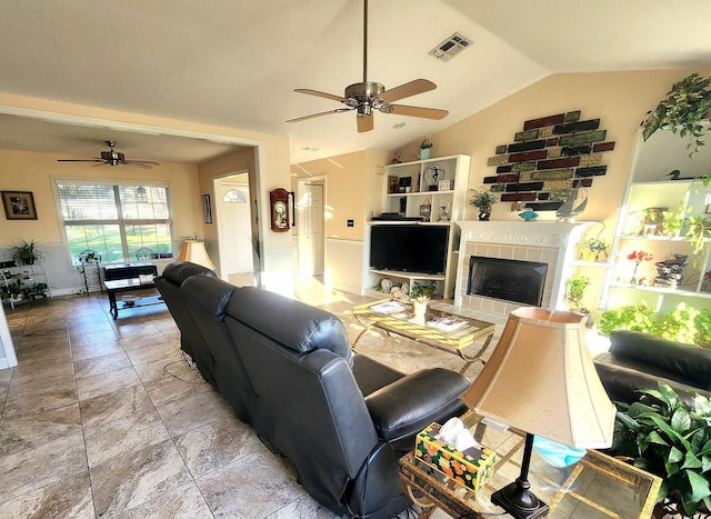 living room with a ceiling fan, lofted ceiling, visible vents, and a tile fireplace