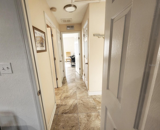 hallway featuring visible vents and baseboards