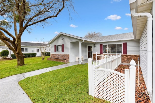 ranch-style home featuring brick siding, fence, a front lawn, and roof with shingles