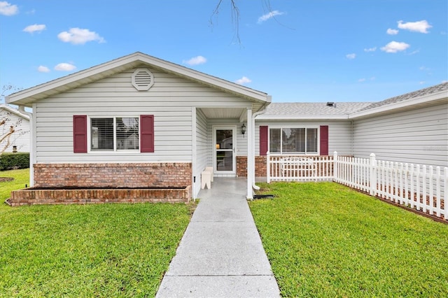 ranch-style home with a front yard, brick siding, and fence