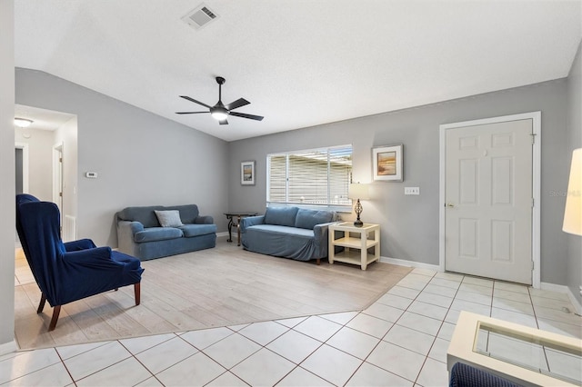 living area with light tile patterned floors, baseboards, visible vents, a ceiling fan, and lofted ceiling