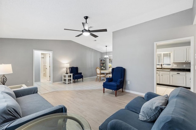 living area featuring lofted ceiling, light wood-style flooring, baseboards, and ceiling fan