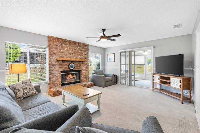 living area with light colored carpet, a healthy amount of sunlight, visible vents, and a brick fireplace