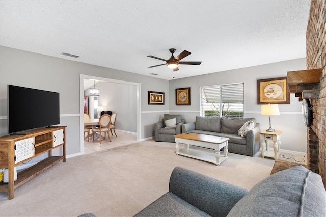 living room featuring light tile patterned floors, visible vents, a ceiling fan, light colored carpet, and a textured ceiling