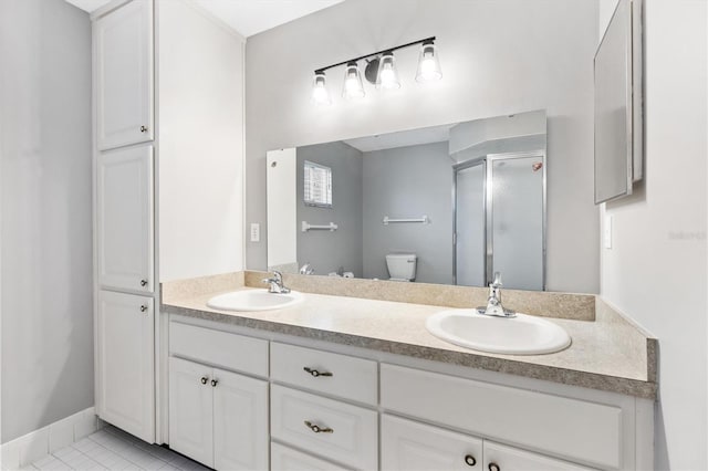 bathroom featuring double vanity, a stall shower, a sink, and toilet