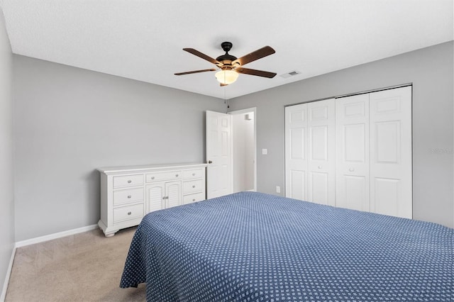 bedroom featuring a closet, light colored carpet, visible vents, ceiling fan, and baseboards