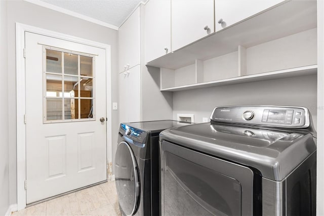 laundry room with a textured ceiling, light wood finished floors, independent washer and dryer, and cabinet space