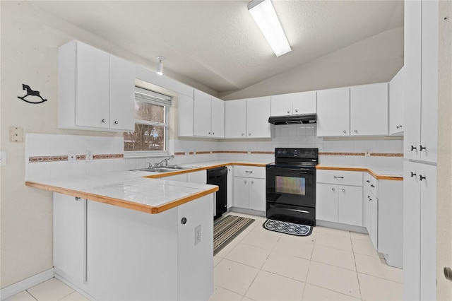 kitchen featuring under cabinet range hood, a peninsula, vaulted ceiling, black appliances, and tasteful backsplash