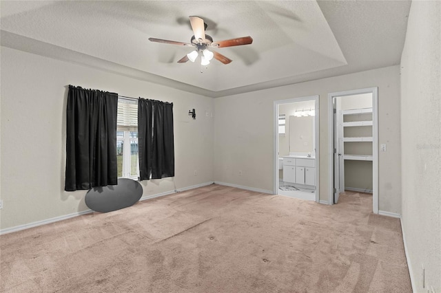 spare room featuring light carpet, a tray ceiling, a textured ceiling, and baseboards