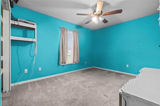 carpeted empty room featuring ceiling fan, baseboards, and a textured ceiling