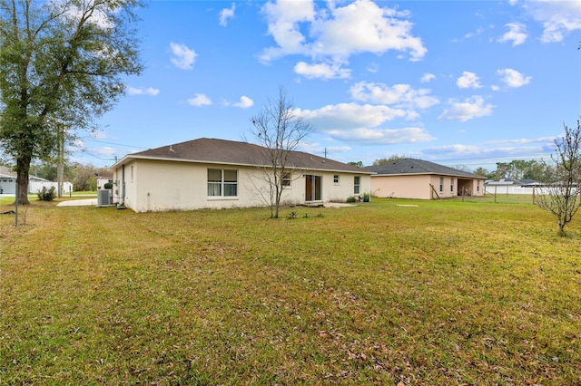 back of property with a lawn, stucco siding, fence, and central air condition unit