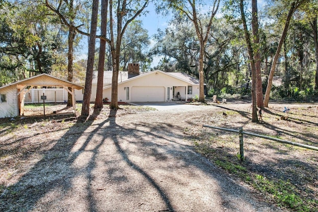 ranch-style house with dirt driveway, a chimney, an attached garage, and fence