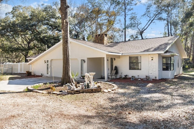 view of front of property featuring an attached garage, a chimney, concrete driveway, and stucco siding