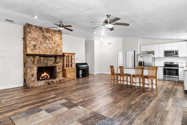 living room with visible vents, dark wood-type flooring, vaulted ceiling, a textured ceiling, and baseboards