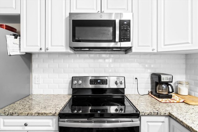 kitchen featuring stainless steel appliances, white cabinets, light stone counters, and tasteful backsplash