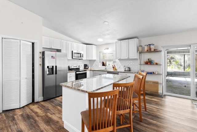 kitchen with white cabinets, light stone counters, a kitchen breakfast bar, a center island, and stainless steel appliances