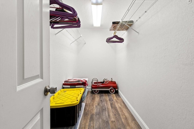 walk in closet with dark wood-style flooring