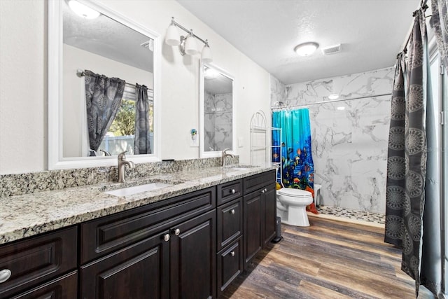 full bath featuring visible vents, a sink, a marble finish shower, and wood finished floors