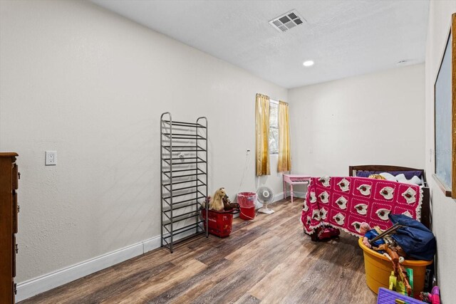 game room with visible vents, a textured ceiling, baseboards, and wood finished floors