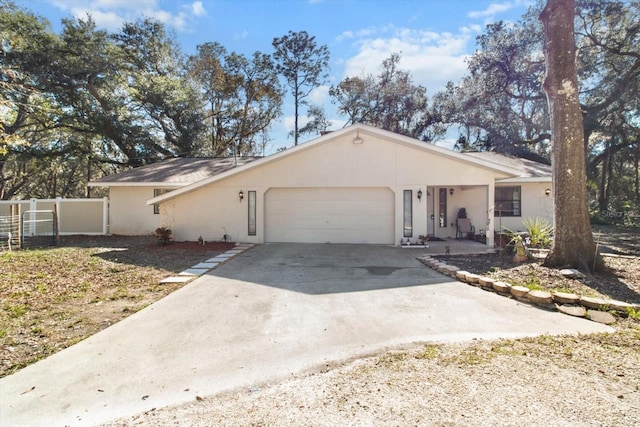 ranch-style house with concrete driveway, an attached garage, fence, and stucco siding