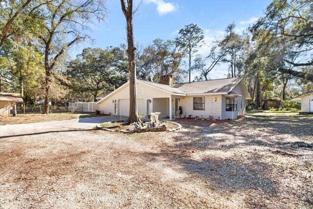 view of front of home featuring a chimney, stucco siding, an attached garage, fence, and driveway