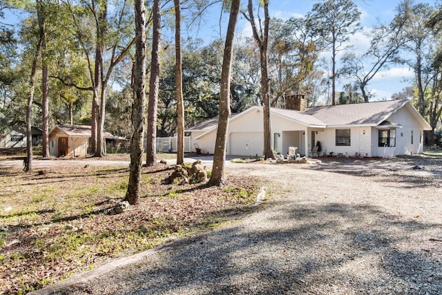 view of home's exterior featuring a garage, gravel driveway, and a chimney