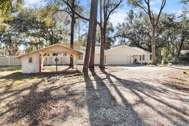 view of front of property featuring driveway, an attached garage, and fence