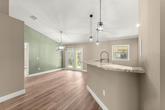 kitchen featuring pendant lighting, light countertops, vaulted ceiling, and french doors