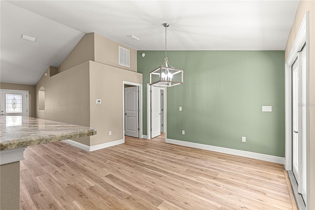 unfurnished dining area featuring a notable chandelier, light wood finished floors, visible vents, vaulted ceiling, and baseboards