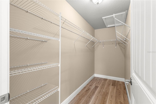 walk in closet featuring attic access and wood finished floors