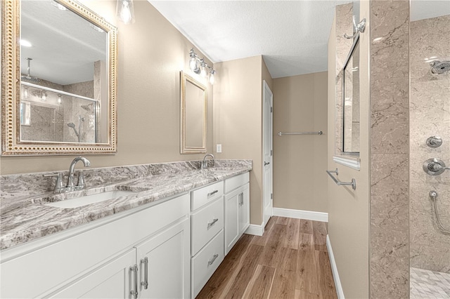 bathroom with a shower stall, baseboards, a sink, and wood finished floors