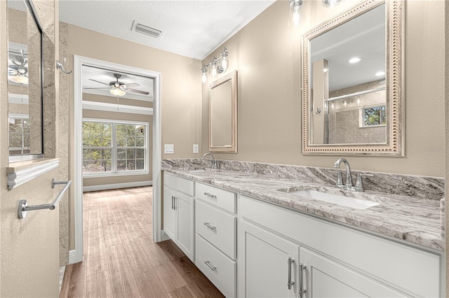 bathroom featuring double vanity, visible vents, a sink, and wood finished floors