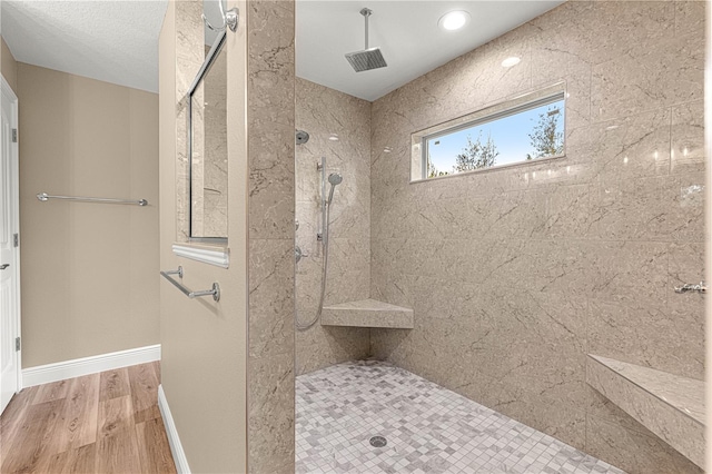 bathroom with a stall shower, wood finished floors, and baseboards